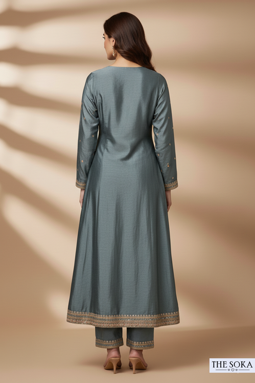 Woman wearing a long teal dress with gold trim on a beige background