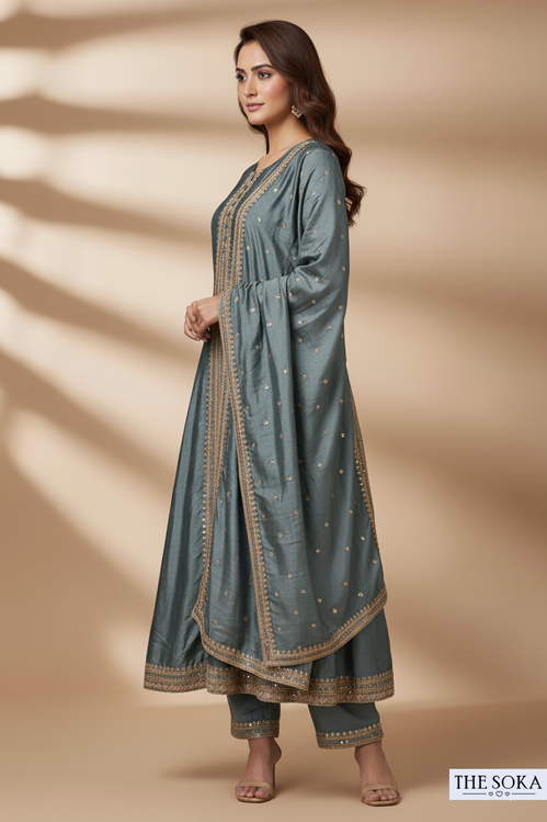 Woman wearing a long, light blue embroidered dress against a beige background