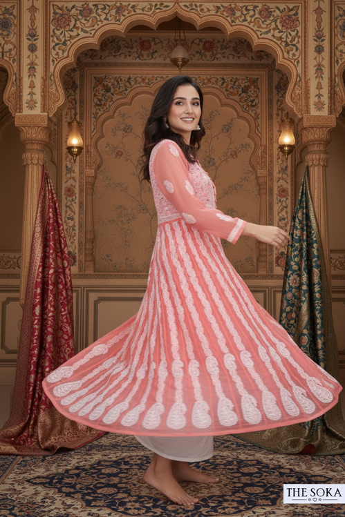 Woman in a pink and white traditional outfit standing in an ornate room.