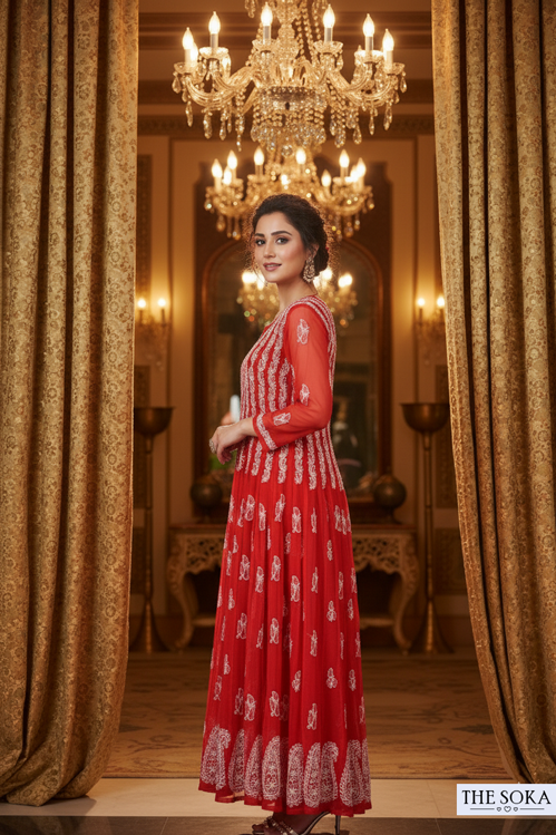 Woman in a red dress standing in an elegant room with chandeliers and gold curtains.