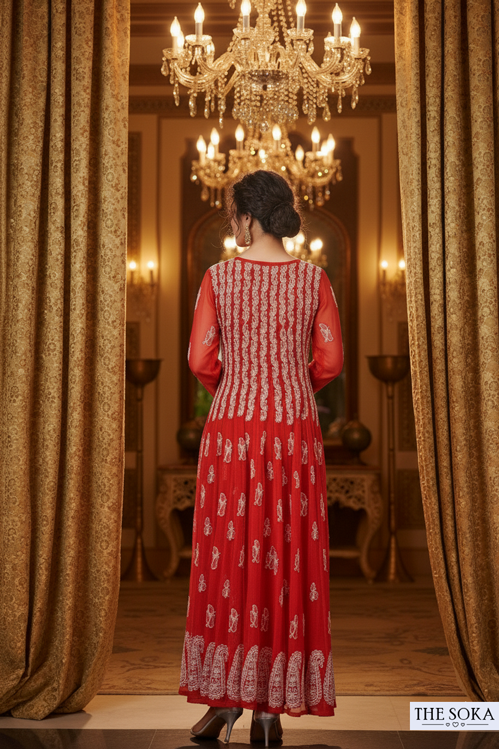 Woman in a red dress standing in a room with chandeliers and gold curtains.