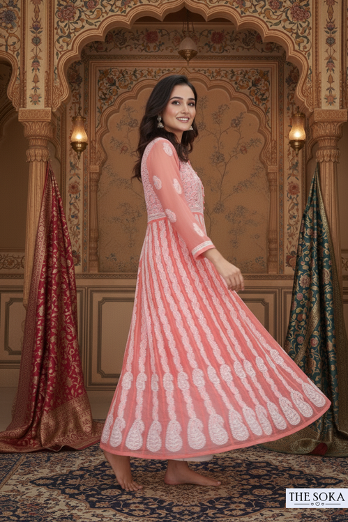 Woman in a pink and white traditional outfit standing in an ornate room.