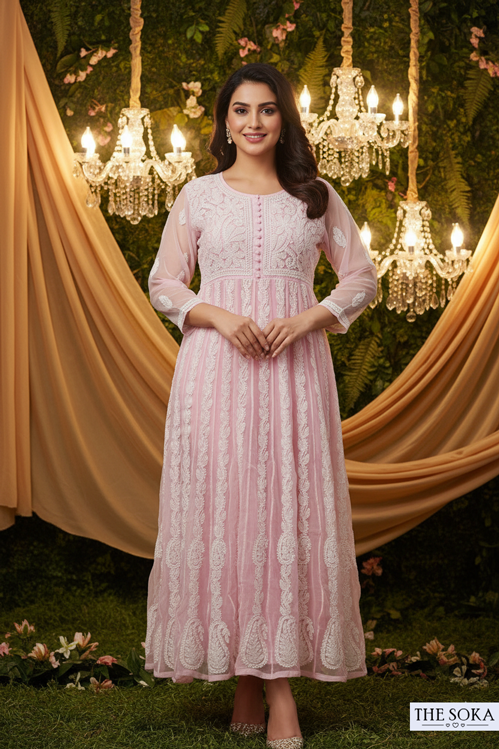 Woman in a pink dress standing in front of decorative lights and draped fabric