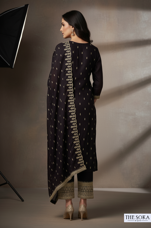 Woman wearing a dark traditional outfit with gold embroidery against a neutral background