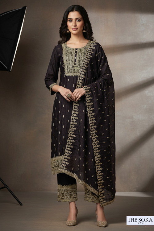 Woman wearing a dark traditional outfit with gold embroidery against a neutral background