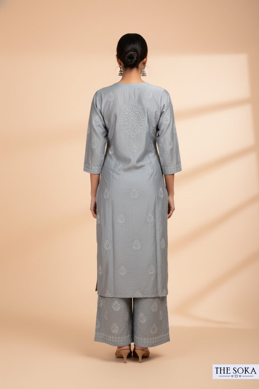 Woman wearing a gray traditional outfit with a subtle pattern on a beige background