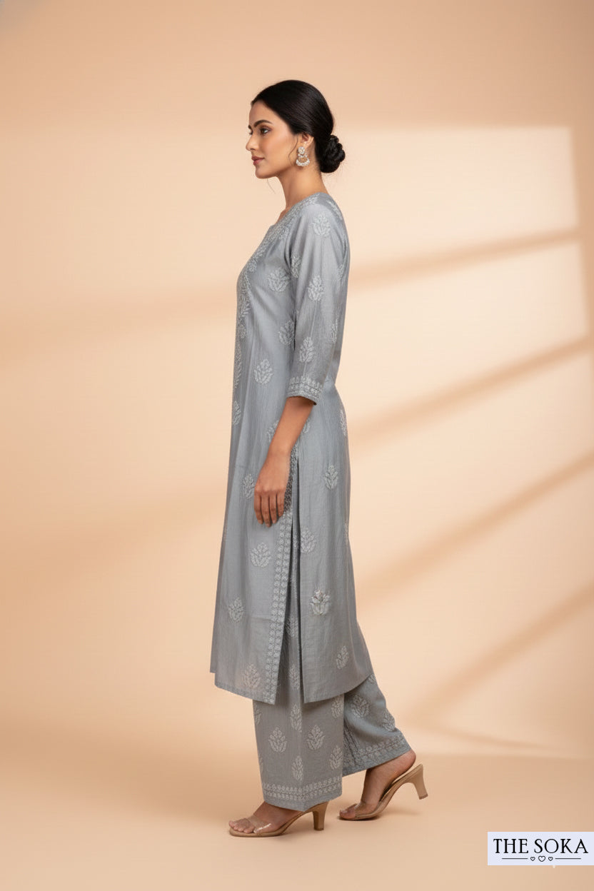 Woman wearing a light gray traditional outfit with a matching dupatta on a beige background