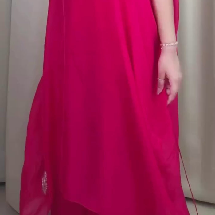 Woman wearing a bright pink traditional outfit with white embroidery against a pink background