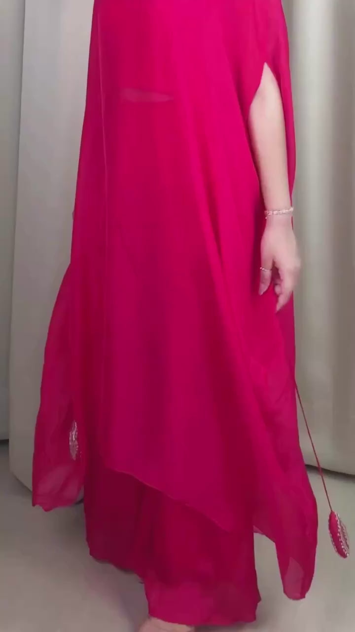 Woman wearing a bright pink traditional outfit with white embroidery against a pink background
