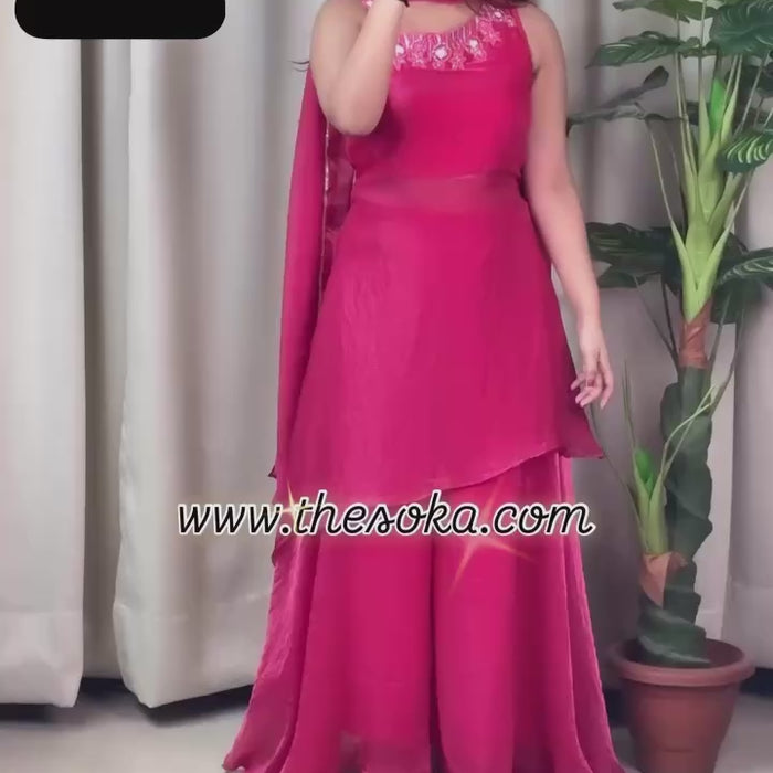 Woman wearing a pink traditional outfit with a drape against a beige background