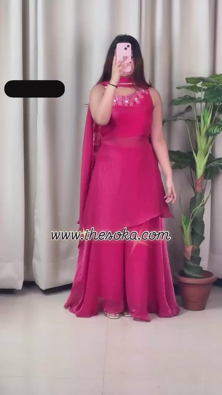Woman wearing a pink traditional outfit with a drape against a beige background